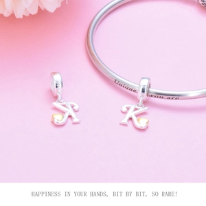 Macro detail of S925 sterling silver letter K pendant with golden heart on a bracelet