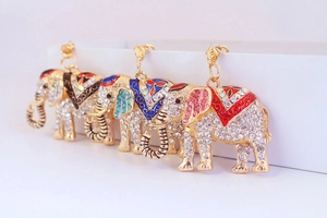 Dettaglio di tre portachiavi a forma di elefante con strass e selle in smalto colorato