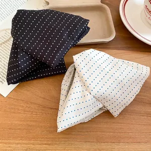 Polka dot fabric hair clips in black and cream colors on a wooden table display