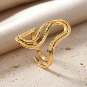 Detail shot of golden wavy irregular ring on stone with silk fabric background