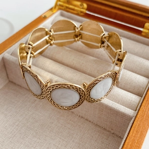 Detailed shot of retro gold leopard bangle with white oval inlay in a wooden gift box