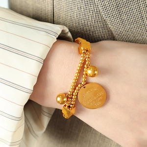 French style 18k gold plated titanium beaded bracelet with round coin charms on a wrist