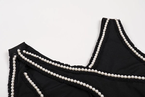 Close-up of black dress with elegant faux pearl trim and wavy lace edge detailing