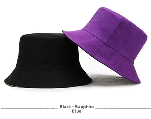 Flat lay detail showing black and royal blue cotton bucket hats with parallel stitching