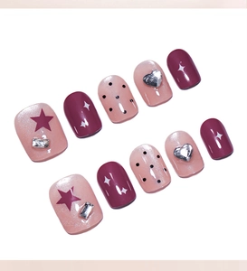 Detailed view of dusty pink press-on nails with black polka dots and silver heart charms