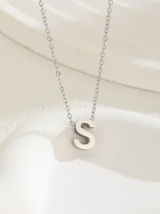 Macro shot of a polished silver letter S pendant on a delicate stainless steel chain