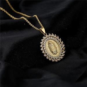 Gold Virgin Mary oval pendant necklace with sparkling cubic zirconia on black fabric