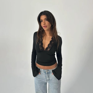 Close-up of deep V-neckline with delicate lace trim on a black long sleeve top