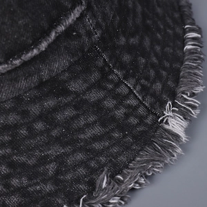 Dettaglio dei bordi sfilacciati e della trama saia di un cappello pescatore in denim