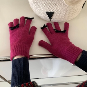 Detail of pink knitted gloves with cute black bow decoration on fingers for winter