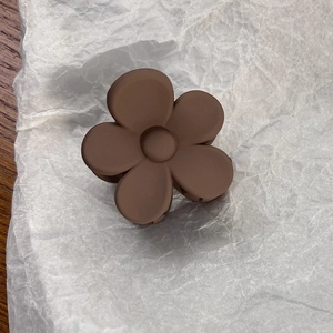 Close-up of matte dark brown flower hair claw clip with a sleek minimalist petal design