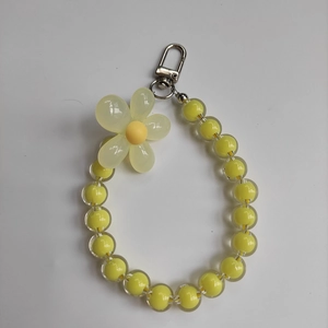 Detail of yellow acrylic beads and beige flower pendant with a silver lobster clasp