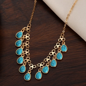 Close-up of bohemian gold chain with turquoise teardrop charms and circular links