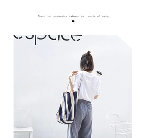 Close-up of blue and white vertical striped canvas tote bag worn on a model's shoulder
