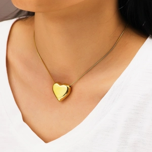 Gros plan du collier avec pendentif coeur doré sur un modèle au fini métal poli