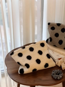 Close-up of fluffy polka dot cosmetic bags with lamb wool texture on a wooden table