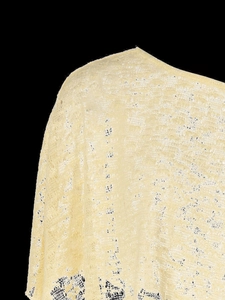 Close-up of light yellow lace knit fabric showing intricate hollow-out crochet patterns