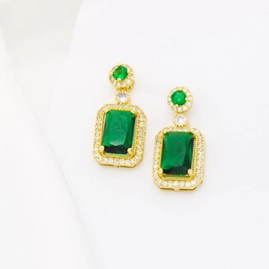 Detail of emerald green crystal earrings with sparkling white zircon halo in gold finish