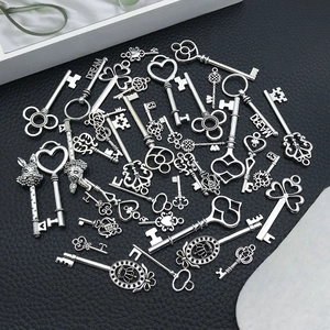 Assorted vintage silver alloy key pendants and charms displayed on black leather background