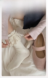 Close-up of cream knit socks featuring delicate lace edges and elegant ribbon bows