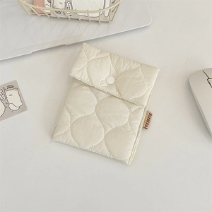 Close-up of cream quilted cosmetic pouch with snap closure and soft padded texture