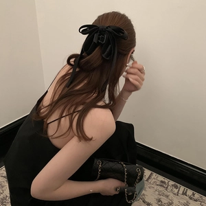 Detail of elegant black satin bow claw clip accessory on woman's styled hair