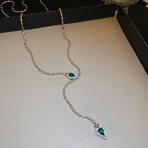 Detail of silver snake chain necklace with emerald green teardrop pendant and crystal halo