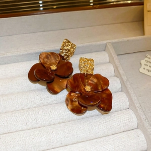 Close-up of vintage brown floral resin earrings with textured gold metal details