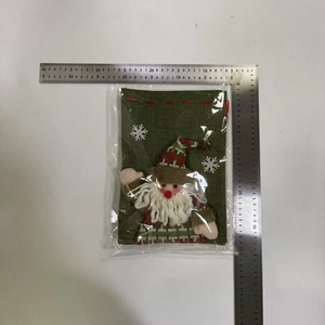 Detailed view of dark green Christmas gift bag with Santa Claus plush and measuring tape