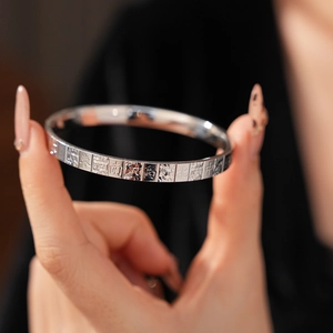 Detail shot of silver metal bangle with engraved mahjong characters and wave patterns