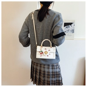 Detail of white PU crossbody bag with red cherry embroidery and woven rope handle