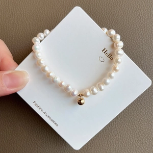 Detailed close-up of natural freshwater pearl bracelet with a 14K gold bead on card