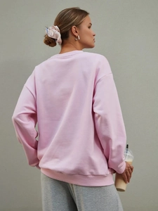 Vista posteriore di una felpa rosa ampia con spalle scese e dettagli a coste