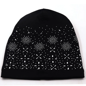 Detailed close-up of a black knit beanie featuring silver rhinestone snowflake patterns