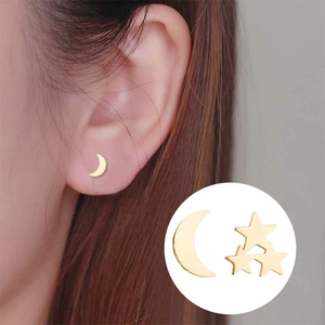 Detail view of gold moon and star stud earrings worn on ear and in close-up shot