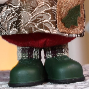 Detailed macro view of Christmas doll featuring green boots and red plush trousers