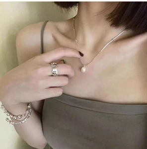 Close-up of a silver minimalist necklace with pearl pendant and matching luxury rings