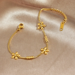 Elegant gold plated flower charm bracelet with crystal accents on a champagne satin background