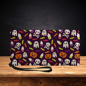 Long faux leather skull wallet with Halloween patterns and wrist strap on wooden surface