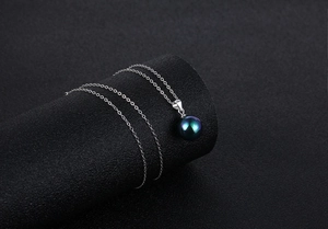 Close-up of a high-luster dark iridescent pearl pendant on a fine silver chain necklace