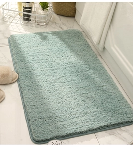 Detailed view of green plush rectangular bathroom rug on marble floor with soft lighting