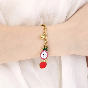 Detail of golden chain bracelet with fruit pendants worn on wrist on white background