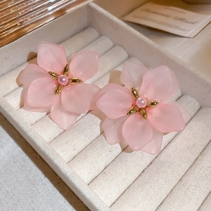 Close-up of pink resin flower earrings with gold stamens in a cream jewelry box