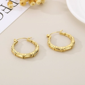 Detailed macro view of golden U-shaped bamboo textured earrings on a ceramic tray