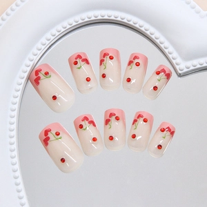 Sweet pink French press-on nails with cherry heart designs and sparkling red rhinestones