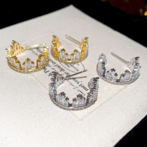 Detailed macro shot of elegant crown-shaped earrings with clear zircon stones on cards