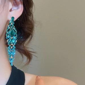 Detail of luxury long green crystal tassel earrings featuring sparkling golden metal setting
