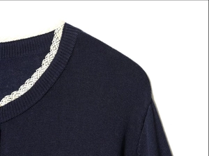 Close-up of a navy knit cardigan featuring a round neckline and white lace trim detail