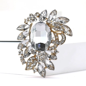 Macro shot of luxury gold brooch with clear oval gemstone and shimmering crystal petals