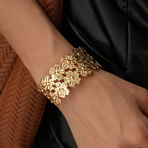 Detailed macro shot of golden daisy floral open cuff bracelet on model wrist